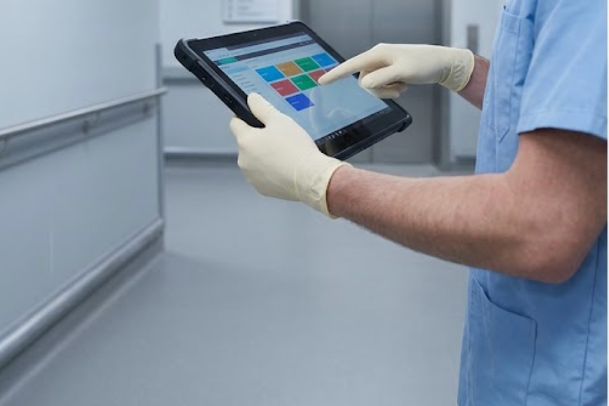 A hospital technician holding a large 13.3-inch rugged tablet while recording readings on a corridor A hospital technician holding a large 13.3-inch rugged tablet while recording readings on a corridor