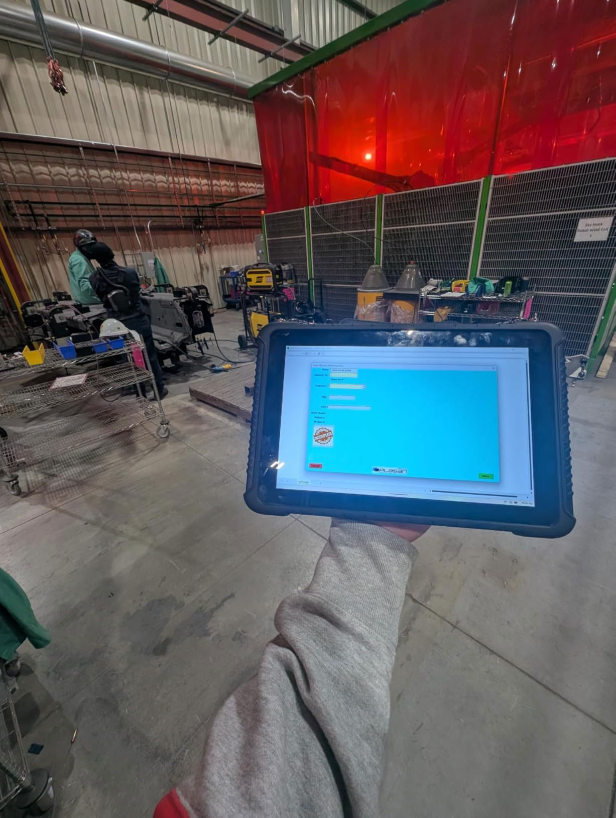 A large rugged Windows tablet held in a press shop showing a hoist inspection form A large rugged Windows tablet held in a press shop showing a hoist inspection form