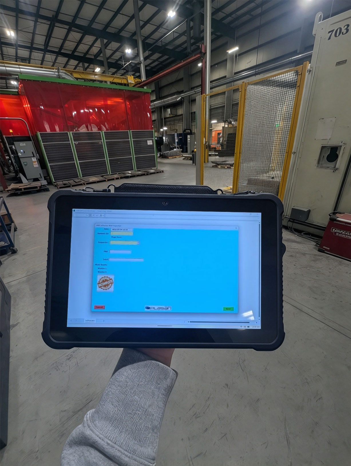 A rugged tablet showing an inspection application on the machine line of a factory A rugged tablet showing an inspection application on the machine line of a factory